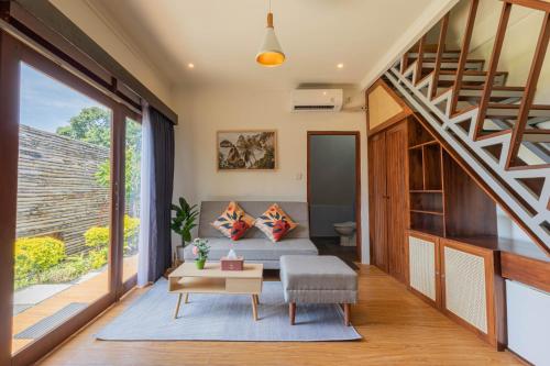 a living room with a couch and a staircase at Kabeh Jati Garden Villa & Restaurant in Nusa Penida