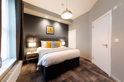 a bedroom with a large bed with yellow pillows at The Spires Serviced Apartments Cardiff in Cardiff