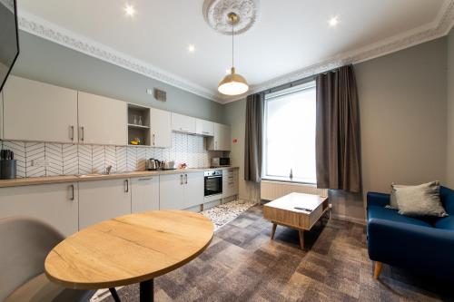 a kitchen and living room with a table and a blue couch at The Spires Serviced Apartments Cardiff in Cardiff