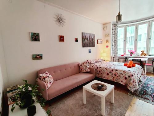 a living room with a pink couch and a bed at Pink Haven, Helsinki Center in Helsinki