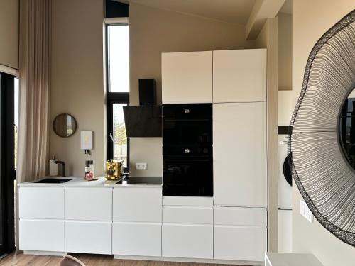 a kitchen with white cabinets and a window at Urriðafoss Waterfall Lodges in Selfoss