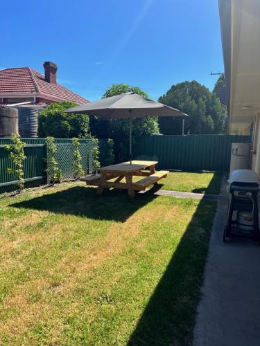 a picnic table with an umbrella in a yard at Kleines Haus Hahndorf in Hahndorf