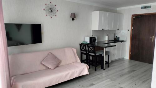 Apartament blisko morza Carmen في كولوبرزيغ: غرفة معيشة مع أريكة وردية وطاولة