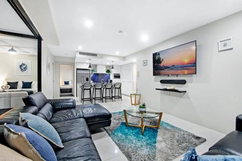a living room with a couch and a tv on a wall at Circle on Cavill Surfers Paradise- 3 Bedroom Superior Apartment in Gold Coast
