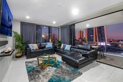 a living room with black leather furniture and a large window at Circle on Cavill Surfers Paradise- 3 Bedroom Superior Apartment in Gold Coast
