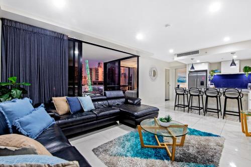 a living room with a black leather couch and a bar at Circle on Cavill Surfers Paradise- 3 Bedroom Superior Apartment in Gold Coast