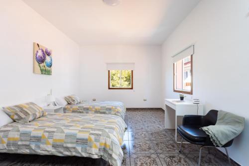 Un dormitorio con dos camas y una silla. en Tegueste Charming House, en Tegueste