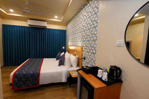 a hotel room with a bed and a mirror at Regenta Inn Bannerghatta Bangalore in Bengaluru