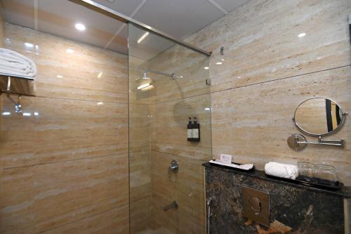 uma casa de banho com um chuveiro e uma porta de vidro em Regenta Inn Bannerghatta Bangalore em Bangalore