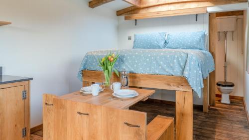 a bedroom with a bed and a table with flowers on it at Betty Shepherd's Hut in Lydney