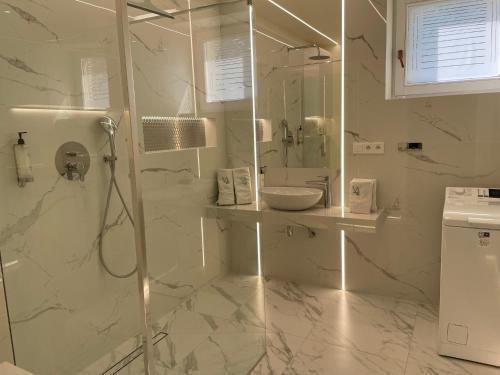 ウストカにあるWczasowa Apartamentの白いバスルーム(シャワー、シンク付)
