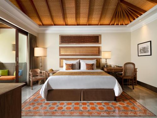 a hotel room with a large bed and a desk at Sudamala Resort, Sanur, Bali in Sanur