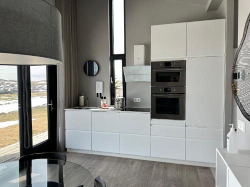 a kitchen with white cabinets and a glass table at Urriðafoss Waterfall Lodges in Selfoss
