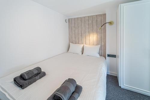 1 dormitorio con 1 cama blanca y 2 almohadas en Ministerija Loft Apartment with parking & AC, en Kaunas