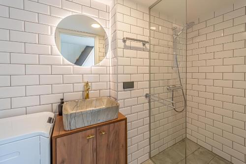 La salle de bains est pourvue d'un lavabo et d'une douche avec un miroir. dans l'établissement Ministerija Loft Apartment with parking & AC, à Kaunas