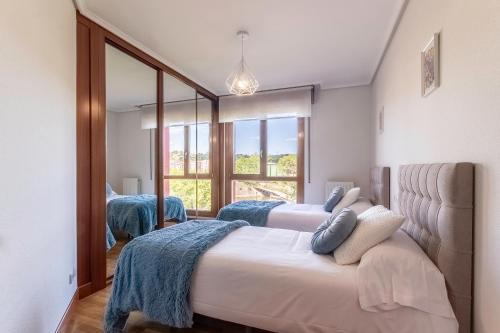 1 dormitorio con 2 camas y un espejo grande en Confort junto a la Ría de Barakaldo, en Barakaldo