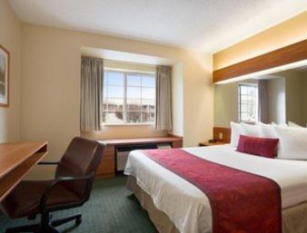 a hotel room with a bed and a desk at Days Inn & Suites by Wyndham Lafayette IN in Lafayette