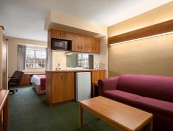 Habitación de hotel con sofá púrpura y cocina en Days Inn & Suites by Wyndham Lafayette IN, en Lafayette
