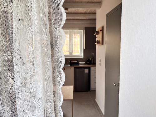 a white curtain in a room with a kitchen at Surf-themed stone house at Kalliopi 2 in Kalliópi