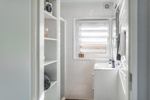 a white bathroom with a sink and a window at Hausboot Küstennebel in Ribnitz-Damgarten
