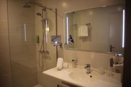 a bathroom with a sink and a shower with a mirror at Mercure Cayenne Royal Amazonia in Cayenne