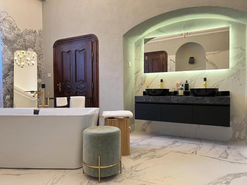 Un baño con bañera y un espejo grande. en Villa Zara Boutique Hotel Resort, en Smolník