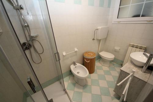 ein Bad mit einer Dusche, einem WC und einem Waschbecken in der Unterkunft Residence Verdena appartamento 03 in Rosolina Mare