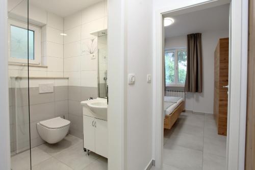 a white bathroom with a toilet and a sink at Sea View Apartments Portoroz ZM in Portorož
