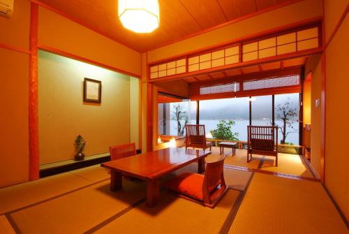 ein Esszimmer mit einem Tisch, Stühlen und Fenstern in der Unterkunft Ginka in Toyooka