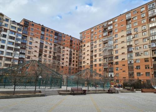 a park with benches in front of tall buildings at 1 bedroom Seaside apartments in Green Park 1 комнатная квартира in Aktau