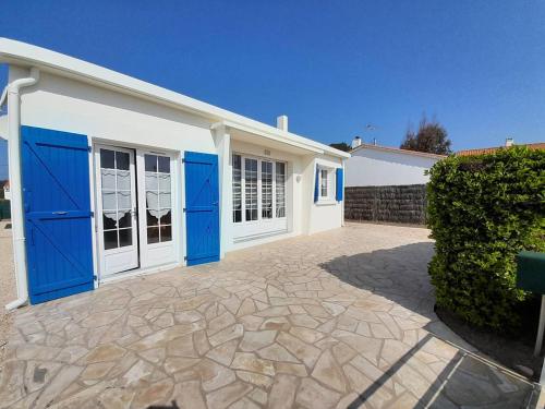 une maison avec des portes bleues et une allée en pierre dans l'établissement Charmante villa 3 chambres, jardin clos, à 700m de la plage - rue calme et bien située - FR-1-324-26, à Saint-Hilaire-de-Riez
