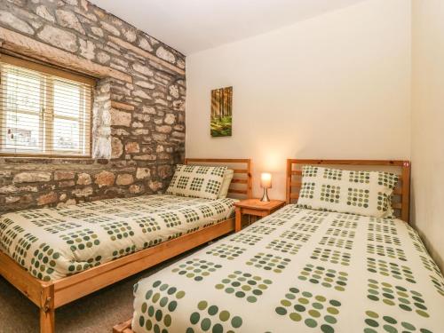 sypialnia z 2 łóżkami i kamienną ścianą w obiekcie Aqueduct Cottage w mieście Abergavenny