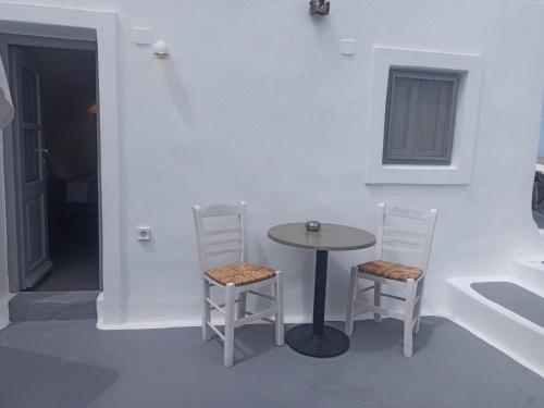 a table and two chairs in a white room at AQUA SERENITY LUXURY SUITES SANTORINI in Foinikiá