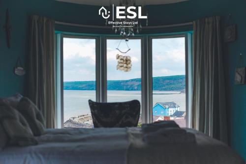 a bedroom with a large window with a view of the water at Beautiful En Suite 5 Bedroom Home with Sea Views in New Quay