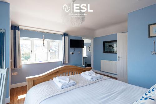 a bedroom with blue walls and a bed with towels on it at Beautiful En Suite 5 Bedroom Home with Sea Views in New Quay