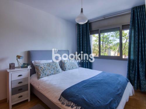 ein Schlafzimmer mit einem Bett mit blauer Decke und einem Fenster in der Unterkunft Gavines del Port in Platja  d'Aro