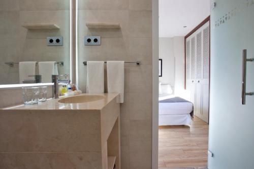a bathroom with a sink and a bedroom at Espahotel Plaza Basílica in Madrid