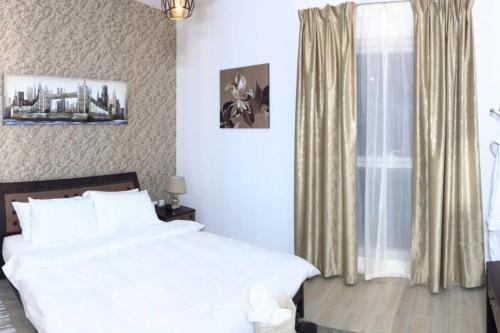 a bedroom with a white bed and a window at Cowboy Charm 1BR Apartment on Yas Island in Abu Dhabi