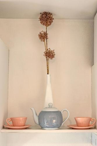 a vase with flowers in it on a shelf with two cups at Appartement la Toscanelle - Quartier historique - Gaillac in Gaillac