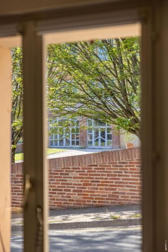 a window view of a brick wall and a building at Appartement la Toscanelle - Quartier historique - Gaillac in Gaillac