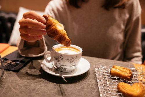 a person holding a croissant and a cup of coffee at Bilder Boutique Hotel in Bilbao