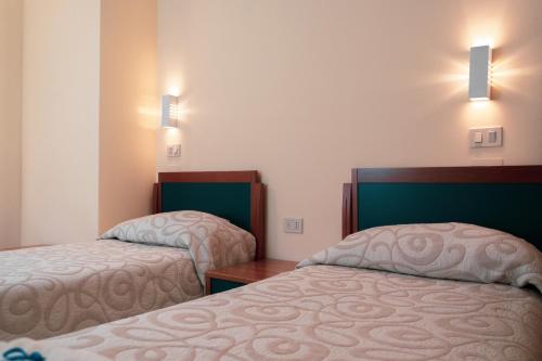 a hotel room with two beds and two lights at Carpediem Assisi Living Club in Piano Delle Pieve