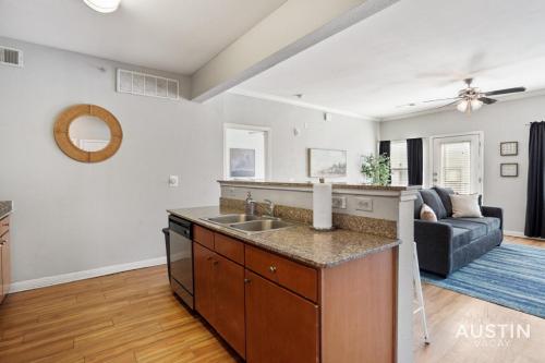 a kitchen with a sink and a living room at King Beds and Memory Foam Sleeper in Vibrant ATX Apt in Austin
