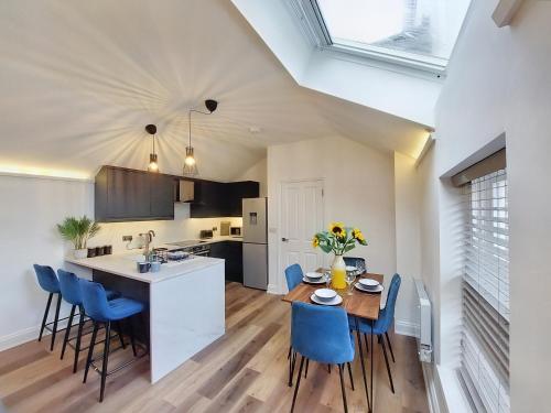 a kitchen and dining room with a table and blue chairs at The Yorkshire Hosts - Langton Lodge Apt.8 in Wakefield