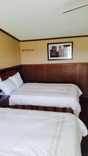 two beds in a hotel room with white sheets at Grand Inn in Big Lake