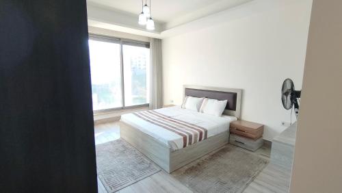 a white bedroom with a bed and a window at Bridge apartments in Amman