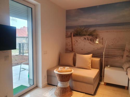 una sala de estar con un sofá y una mesa en Apartament Beige z ogródkiem, en Dziwnówek