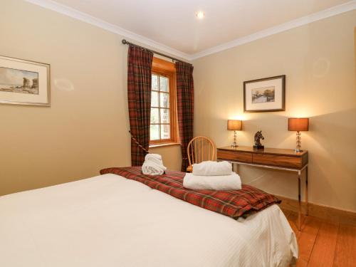 een slaapkamer met een bed, een bureau en een raam bij Glen Cruick in Kirriemuir