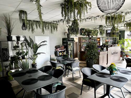 a restaurant with tables and chairs and plants at Villa Gāles Hotel in Saulkrasti