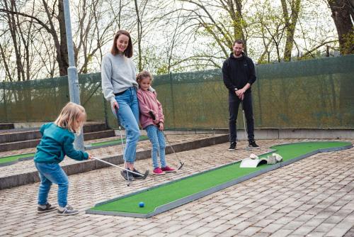 a woman and two children playing a game of golf at HOTEL AGRI in Soběšice